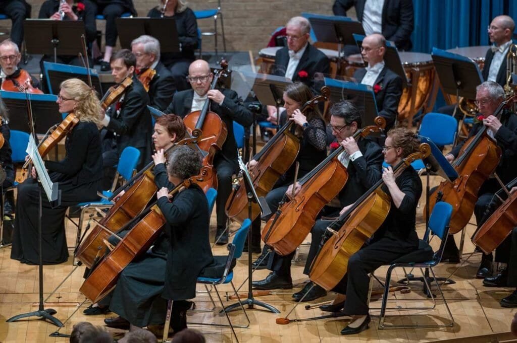 A orchestra performing on stage with string instruments during a concert.